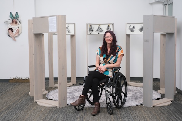 photo - Artist Amy J. Dyck sits amid her work “Bed Desk,” one of the pieces in her solo exhibit, Portals to Elsewhere, which opened at the Zack Gallery last month